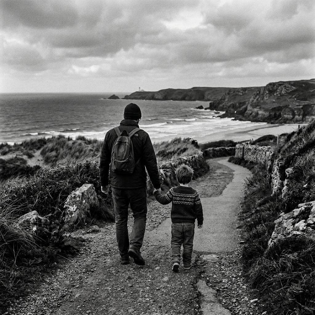 Adult and child walking on coastal path with ocean and cliffs in background
